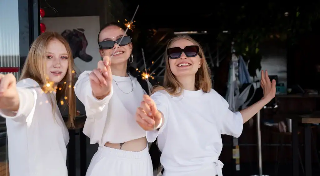 Молодые женщины с бенгальскими спиральками, празднуют и улыбаются, веселье и дружба.